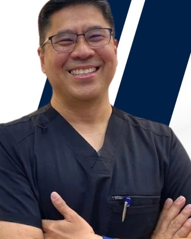 Dr. Ryan Ramos in black scrubs, smiling with arms crossed