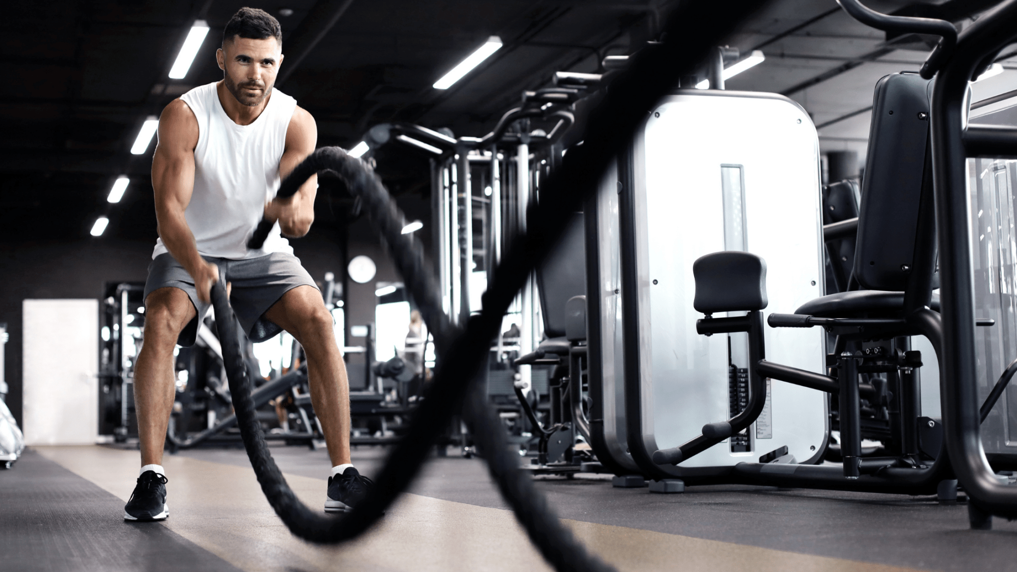 Athletic man training with battle ropes in a gym