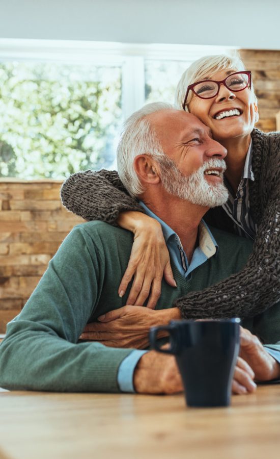 Smiling couple sharing coffee at a kitchen table