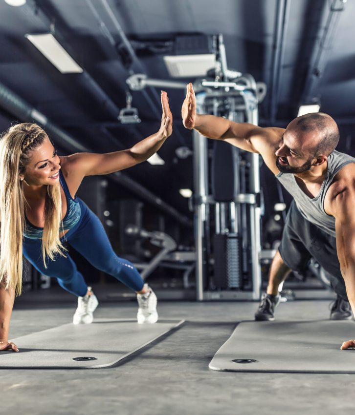 Man and woman high-fiving mid-workout in a gym
