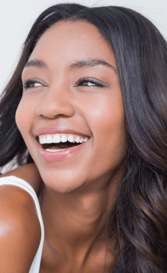 Smiling woman with clear, glowing skin looking over her shoulder