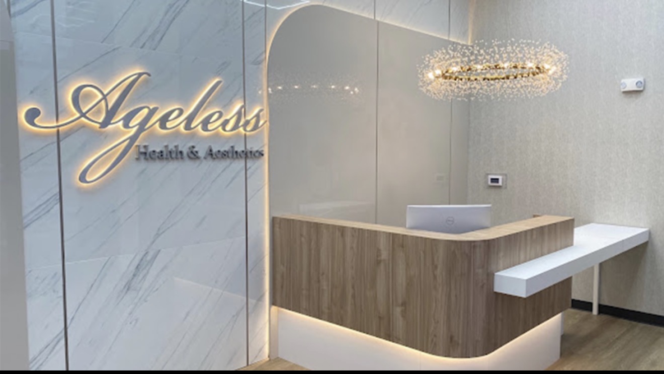 Reception lobby at Ageless Health & Aesthetics with the backlit logo wall and front desk