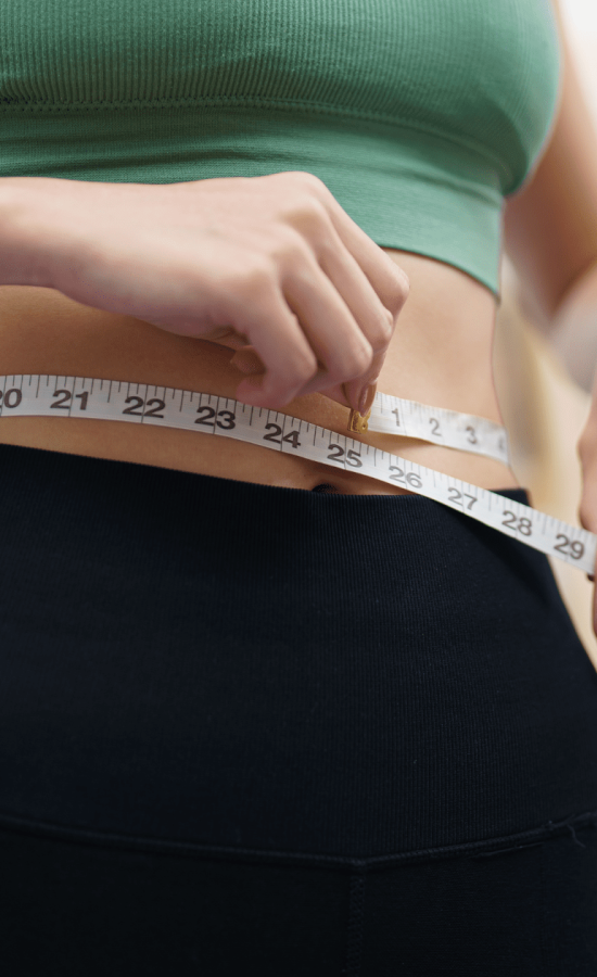 Woman measuring her waist with a tape measure